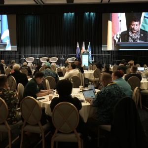 People sat around tables while someone talks on stage