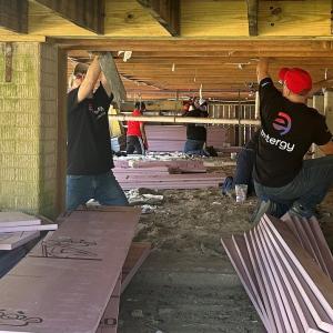 Volunteers installing insulation under a building.