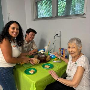 Volunteers sitting a bright green table with an elderly woman