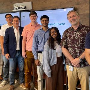 A group of interns and staff in line in an office setting, screens behind them.