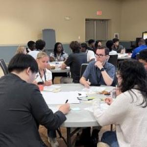 Mathew Sweeney seated with others at a round table in a room with others.
