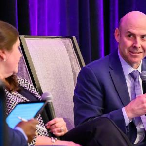 A person with a microphone talking to two others.