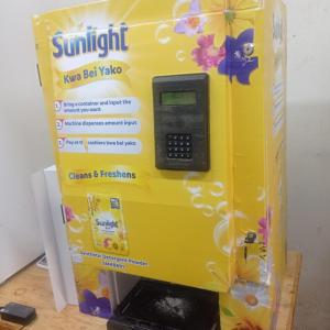 A bright yellow vending machine with "Sunlight detergent" logos.