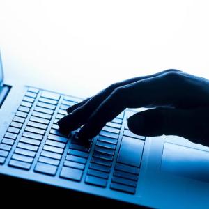 A hand typing on a laptop keyboard.