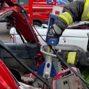 A firefighter using a tool to open a car door.