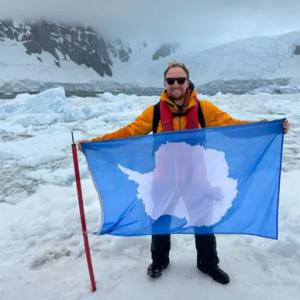 Josh Hasdell holding an Antarctica flag.