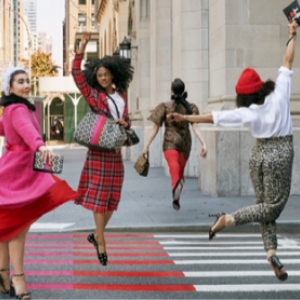Four people dancing on a city street, each wearing a unique kate spade outfit.