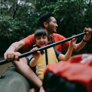 An adult and child kayaking in a body of water.