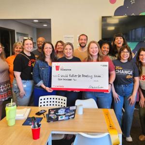 A group posed with a large check