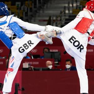 two people in a fighting match, wearing protective gear, in a stadium