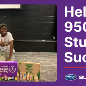 A student and an adult behind school supplies, giving thumbs up