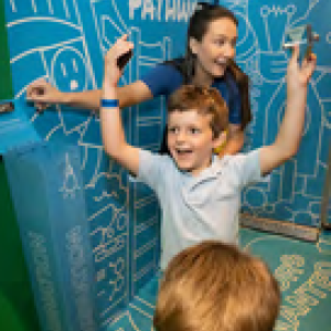 A child cheering by an adult pointing to a wall with writing on it. 
