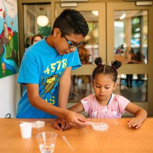 Two kids working together on an experiment on a table
