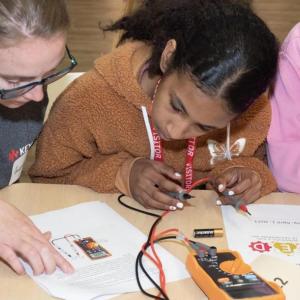Kids working together with written instructions and electronics, wires and batteries.