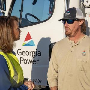 Two people talking next to a Georgia Power truck.