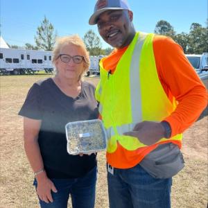 Two people posed with a container of food