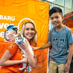 person holding a kitten next to a child