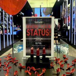 MAC in-store display table with red ribbons and a sign "Know your status".