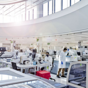 A crisp white lab with employees working with machinery.