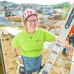 A smiling volunteer on a ladder.