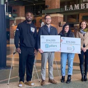 Representatives from The Green Bay Packers and Tork shown holding signs for the $14,500 that was donated.