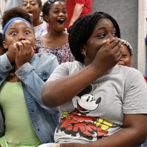 children gasp, and have hands over their mouths, some have huge smiles