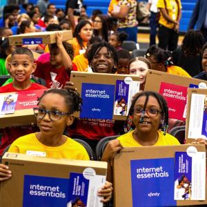 Children seated in a group, each holding a new laptop.
