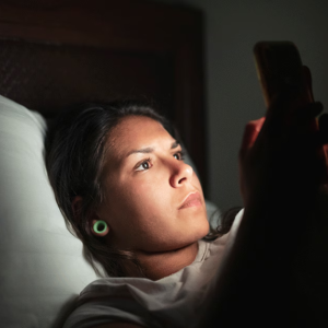 person looking at smartphone at night in bed
