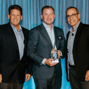 Three people stood next to each other holding an award, in front of a blue backdrop  