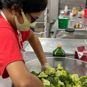Volunteer mixing broccoli in a bowl
