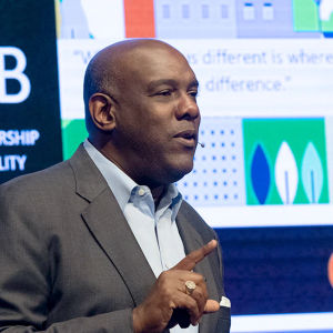 A person speaking with a large display behind them with PNC logo and "Home lending $13.3 B to expand homeownership and economic mobility" visible