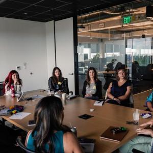 A conference room with a full table of seated peopl.
