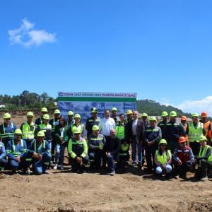 A large group posed outside. Each in high-vis vest and hard hats.