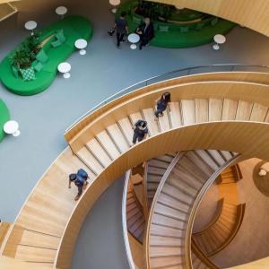 Interior of a spiral wooden staircase and seating areas at different levels.