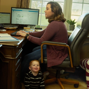 Woman working at a desk with kids crawling beneath her chair