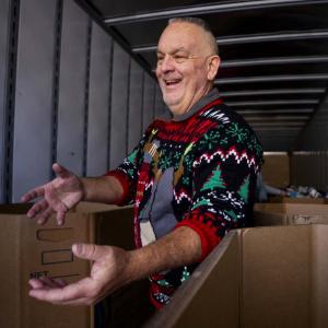 A smiling person loading boxes in a semi trailer.