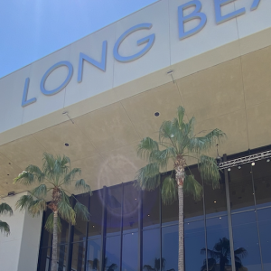 The outside of a 'Long Beach' building that has palm trees outside the windows 