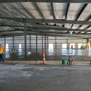A large open building with concrete floor being poured and set.