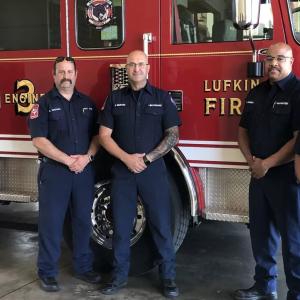 four firefighters standing by a fire truck