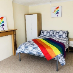 safe house bedroom with a rainbow flag on the bed and rainbow art on the walls
