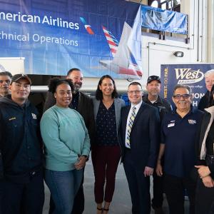 A group of employees and students posed in front of a large banner "American Airlines Technical Operations."