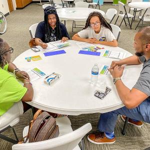 Four people seated at a round table, worksheets in front of them