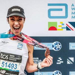 A person wearing medals in front of an Abbott World Marathon Majors back drop 