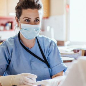 Masked person in scrubs talking to patient