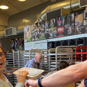 two people packing meals, many tray carts behind them