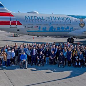 Large group of people stood in front of an aeroplane 