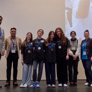 A group of students and presenters on a stage.