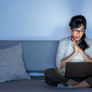 Woman sitting on a couch with open laptop