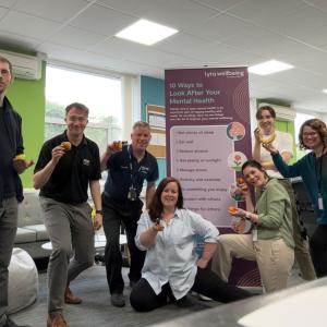 A group holding up a piece of fruit each.