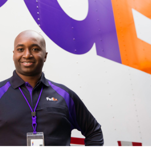 A person posed in front of a truck with "FedEx" on the side.